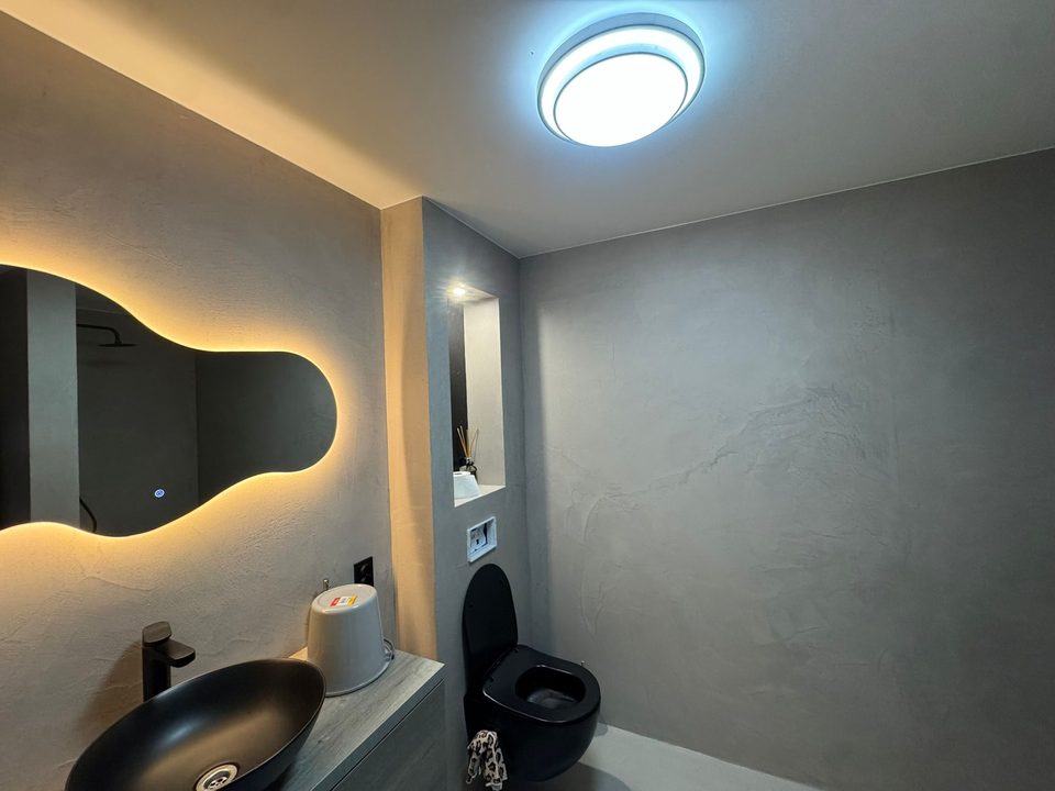 Toiletruimte met grijze beton ciré en zwarte wastafel